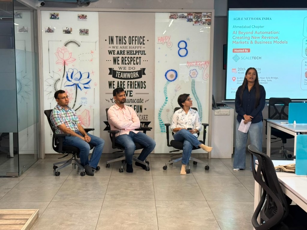 Panel discussion at Agile Network India — AI Beyond Automation event poster on screen, four participants seated in Ahmedabad