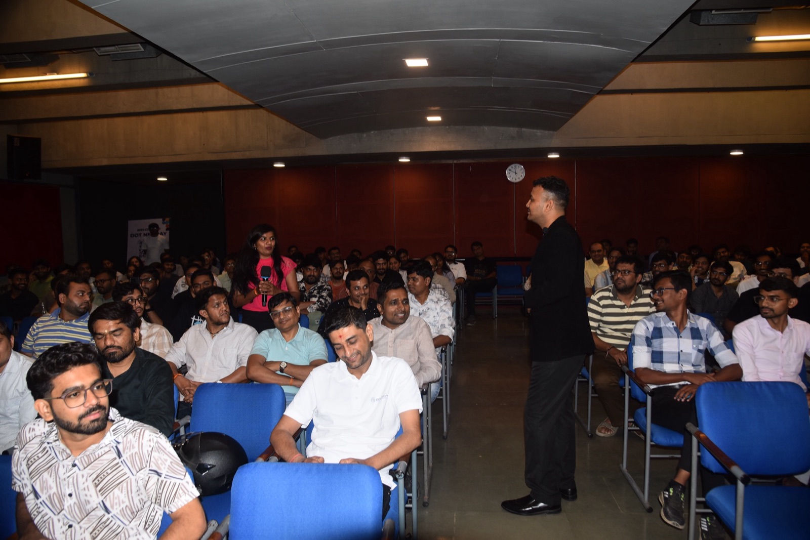 Jigar Joshi walking through a packed audience while presenting on agentic AI at MDCA