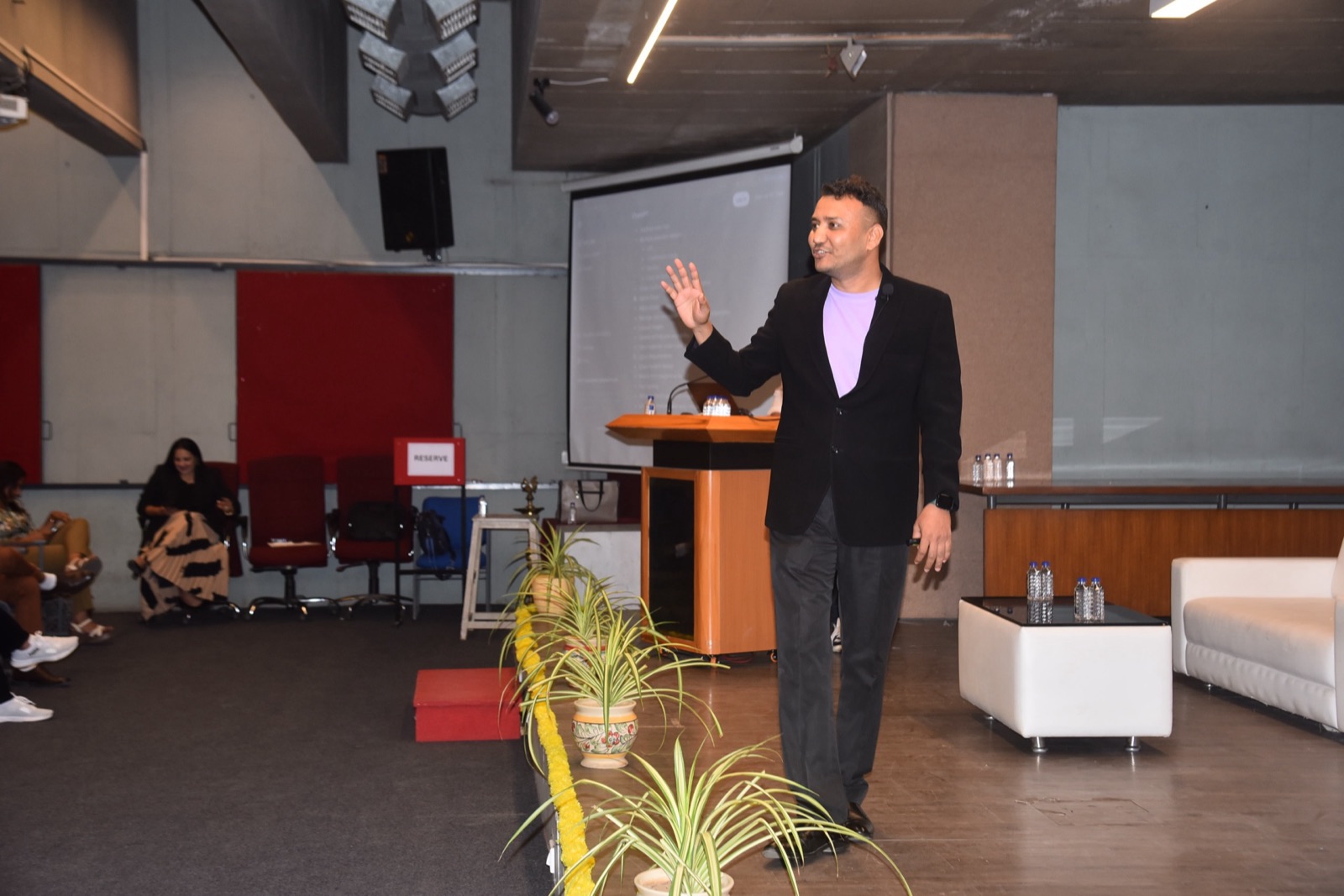 Jigar Joshi walking the stage with arm raised during the agentic AI keynote at MDCA Ahmedabad
